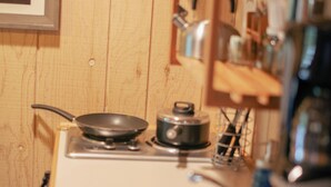Una cocina con armarios de madera, estufa, pileta y diferentes utensilios de cocina.