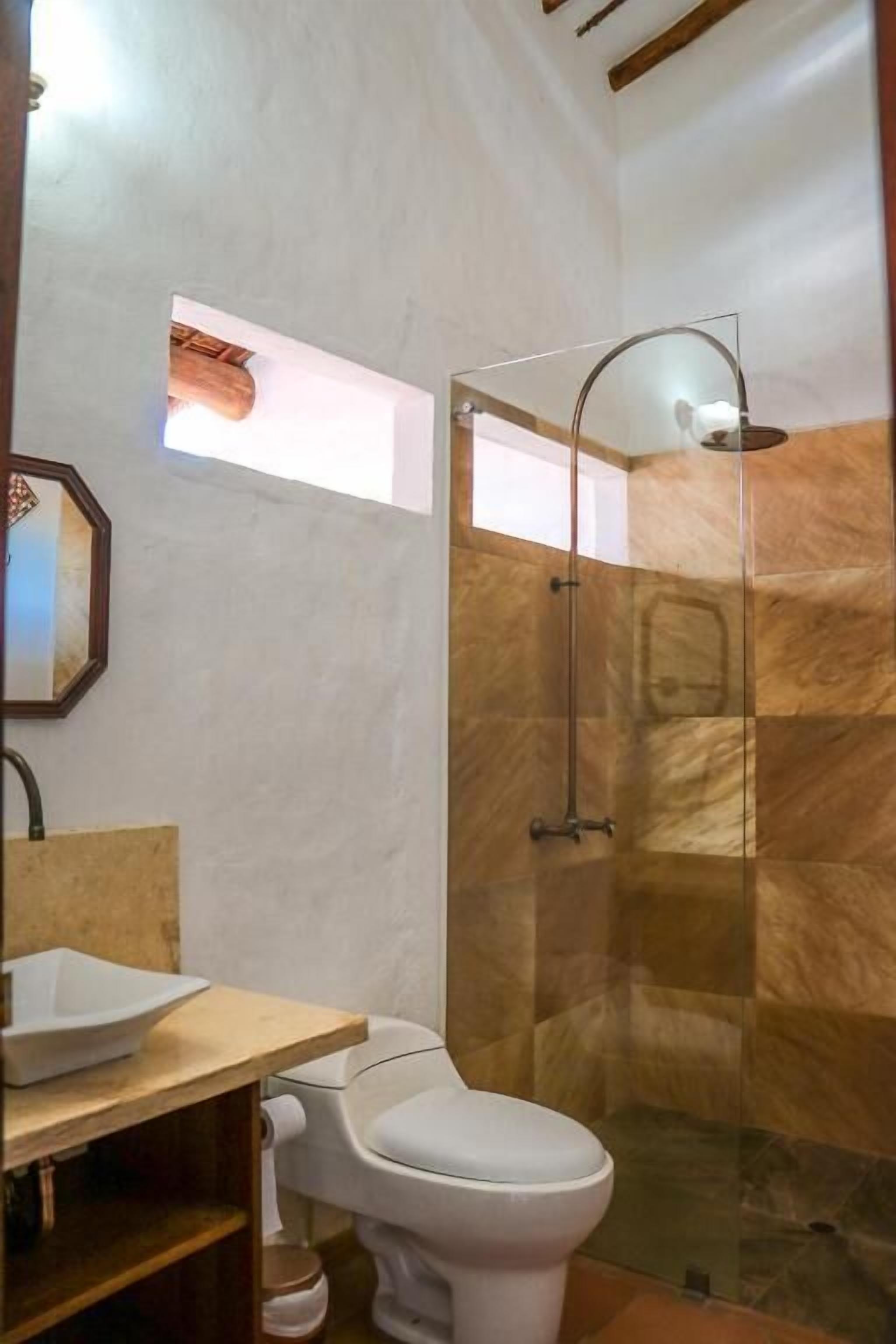Un baño con inodoro, lavabo y zona de ducha con puerta de cristal.