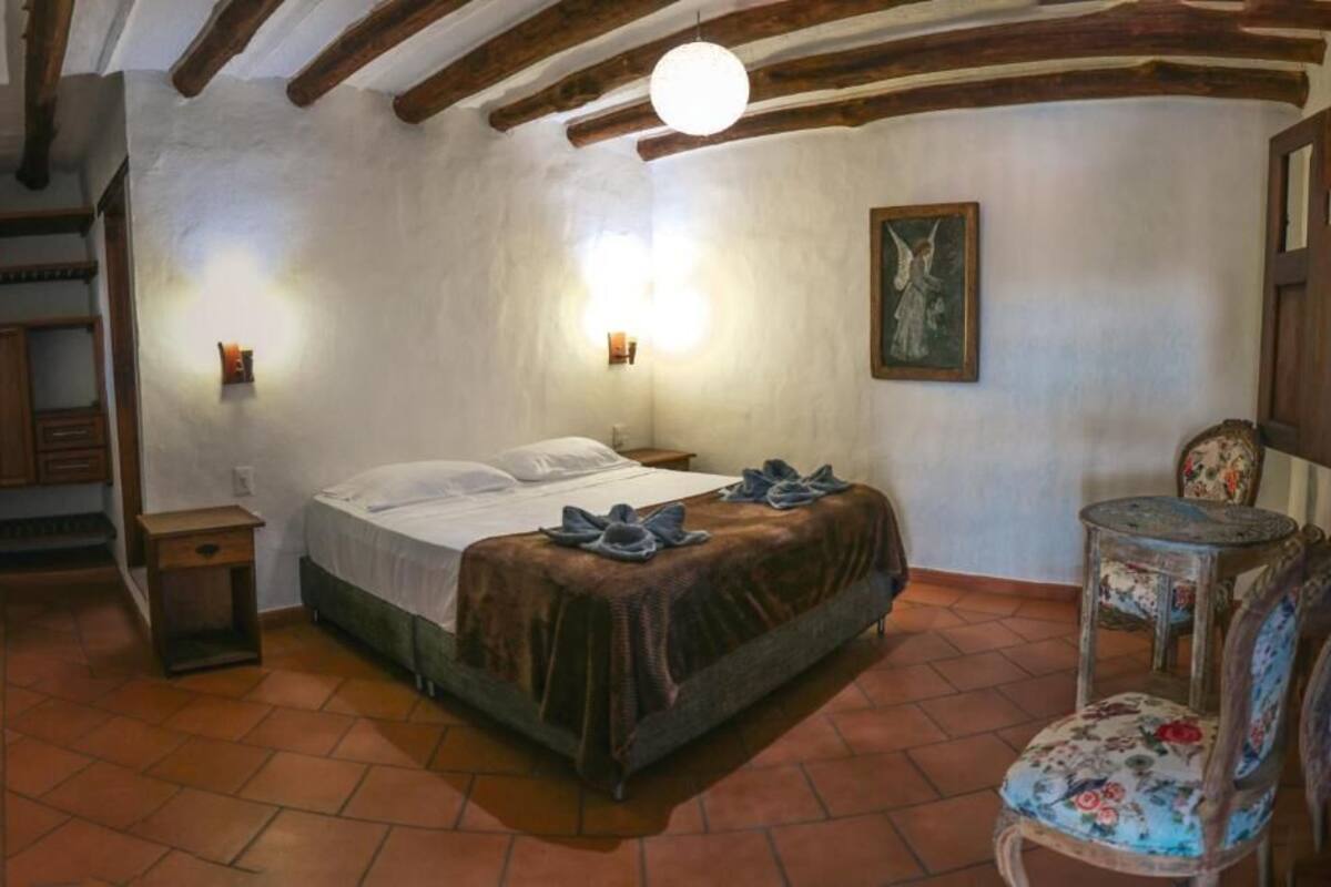 Een slaapkamer met een bed, nachtkastje, stoel en een trap.