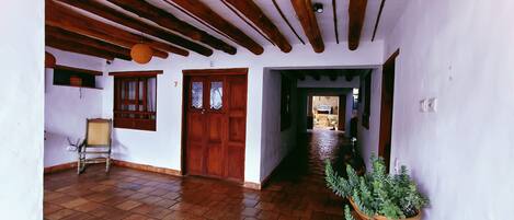 A hallway with wooden beams, a wooden door, and a potted plant.