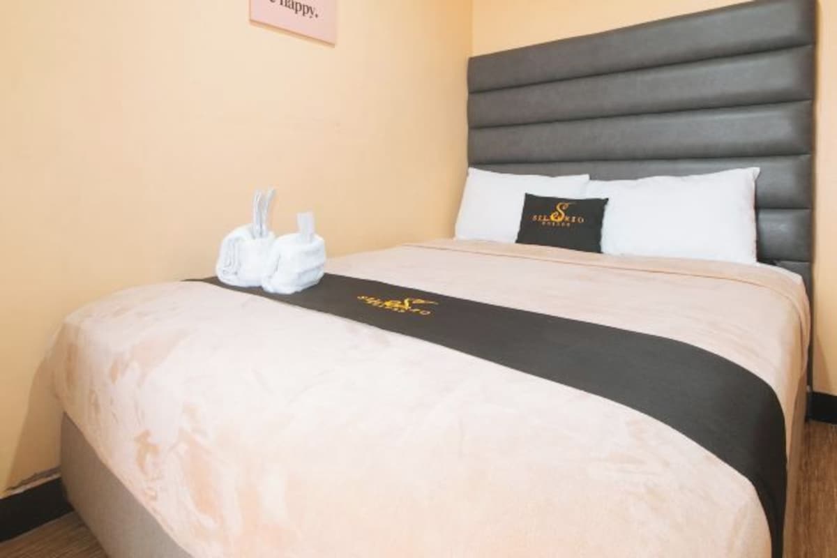 Een hotelkamer met een groot bed, hoofdeinde en een bord aan de muur.