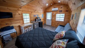 A cozy cabin with a large bed, a small kitchenette, and a TV. - 1 Room Cabin- " The Garage" (Robbinsville)