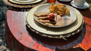 Ein Frühstückstisch im Freien mit Speisen, Getränken und einer Flasche.