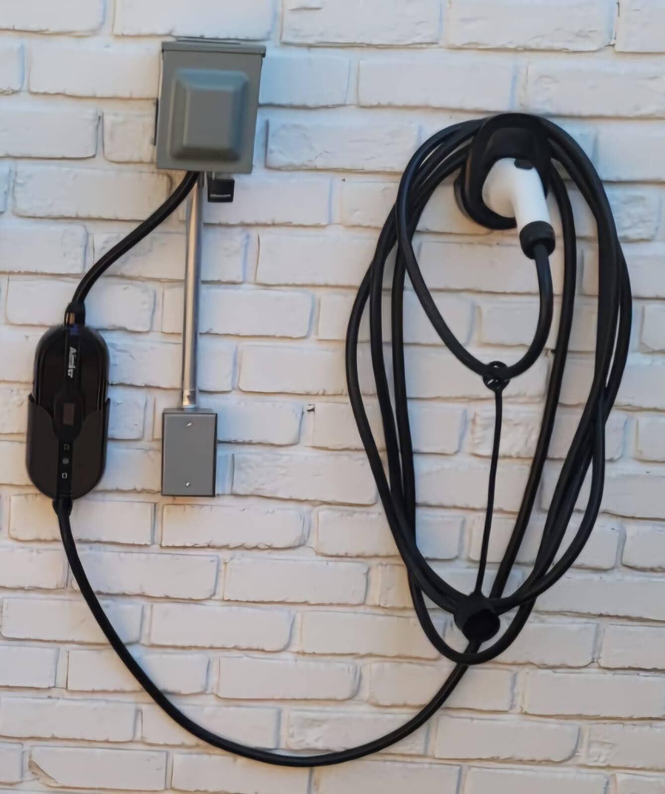 A wall-mounted electrical outlet with a black cable connected to a device.