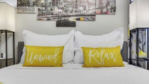 A bed with white bedding and two yellow pillows with the words "Unwind" and "Relax" on them. - Rare Find Atlanta Retreat, this weekend just opened, Near Airpott+EV Charger (Atlanta)