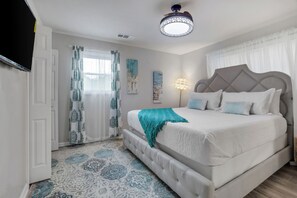 Ein Schlafzimmer mit einem großen Bett, einer Deckenleuchte und gemusterten Vorhängen.