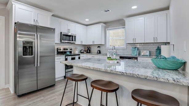 A modern kitchen with white cabinets, stainless steel appliances, a marble countertop, and two bar stools. - Rare Find Atlanta Retreat, this weekend just opened, Near Airpott+EV Charger (Atlanta)