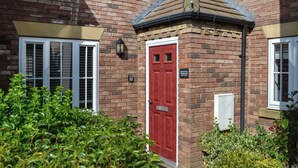 A brick building with a red door, a small window, and a mailbox. - 3 bedroom accommodation in Filey (Filey)