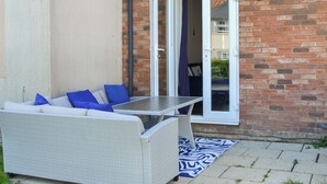 A patio with a wicker sofa, a table, and a patterned rug. - 3 bedroom accommodation in Filey (Filey)