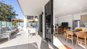 A modern apartment with a patio area, a dining area, and a kitchen. - Iggy's Retreat Huskisson by Latitude South Coast (Huskisson)