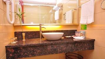 A bathroom with a granite countertop, a white sink, a mirror, a towel rack, and a small trash bin.