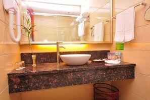 A bathroom with a granite countertop, a white sink, a mirror, a towel rack, and a small trash bin. - Apollo Hotel (Yucheng)