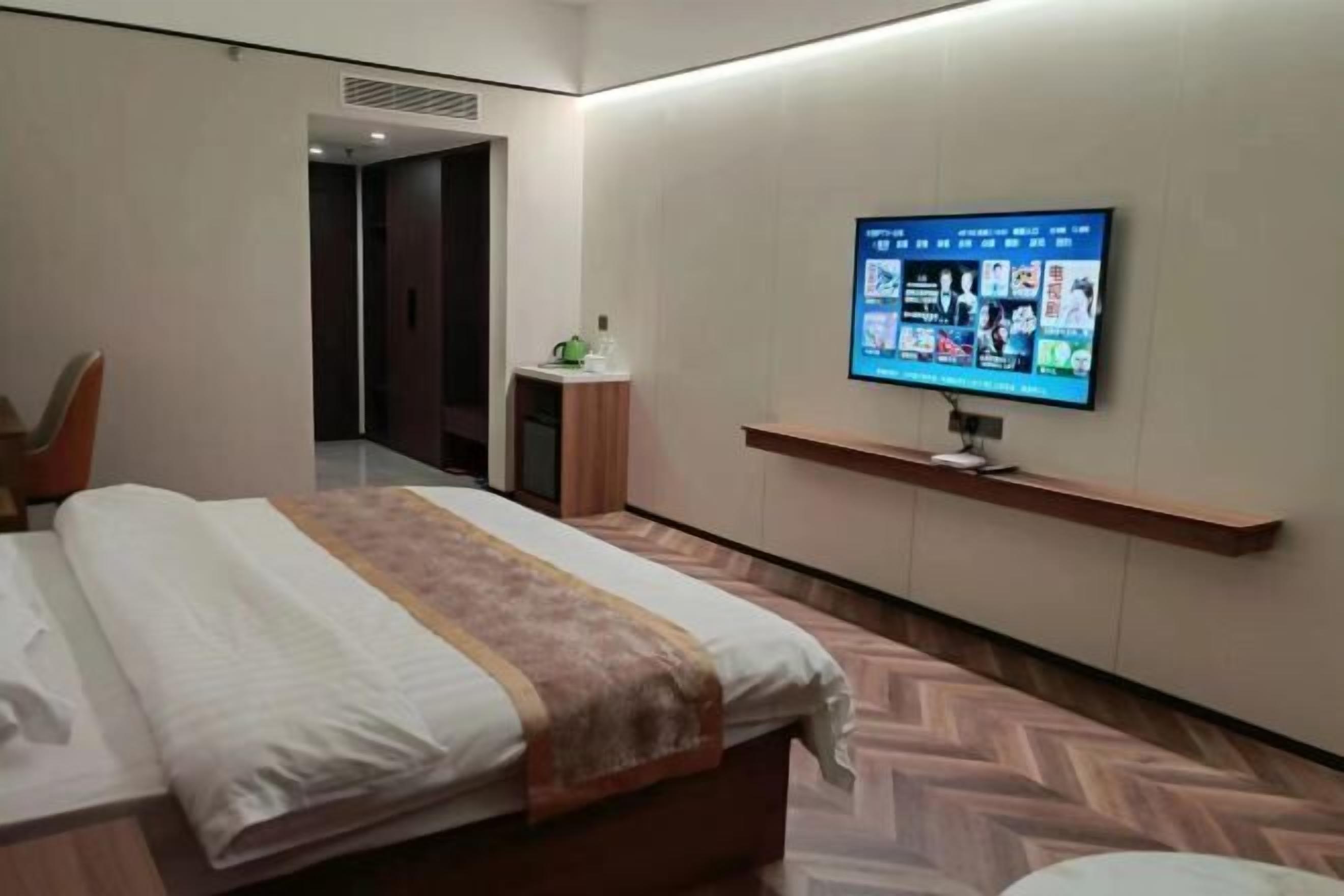 Ein Hotelzimmer mit Bett, Wandfernseher, kleinem Tisch und Stuhl.