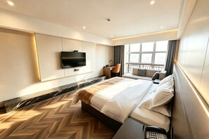 A modern hotel room with a large bed, a flat-screen TV mounted on the wall, a desk with a chair, and a view of the outdoors through large windows. - Apollo Hotel (Yucheng)