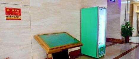 A lobby with a green vending machine, a fire extinguisher, and a sign on the wall.