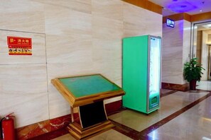 A lobby with a green vending machine, a fire extinguisher, and a sign on the wall. - Apollo Hotel (Yucheng)