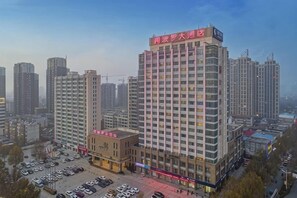A multi-story hotel with a prominent sign, a parking lot, and surrounding high-rise buildings. - Apollo Hotel (Yucheng)