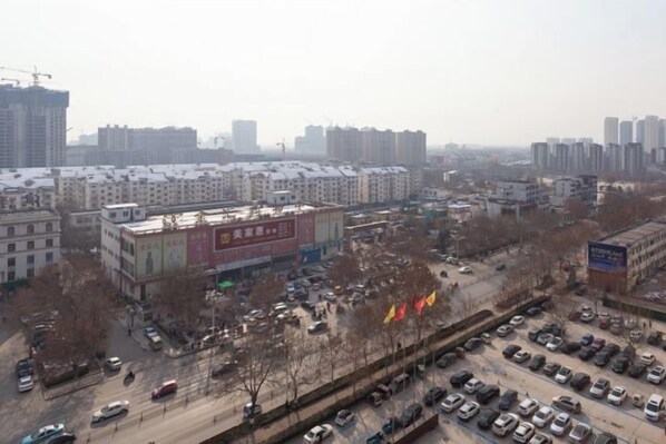 A cityscape with high-rise buildings, a parking lot, and a road with vehicles.