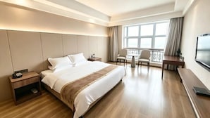A hotel room with a large bed, bedside tables, a desk with a chair, a TV, and a balcony with curtains. - Apollo Hotel (Yucheng)