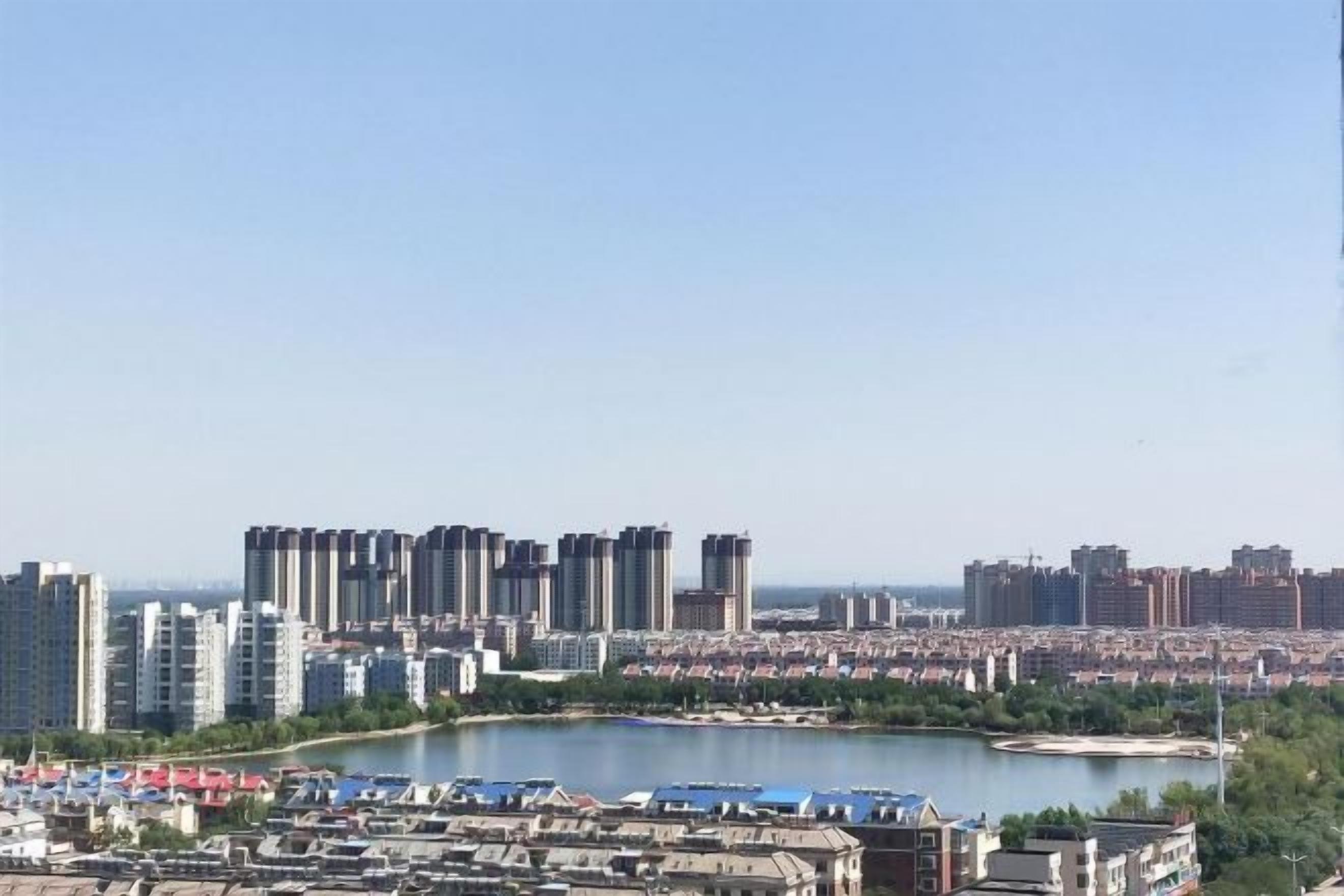 A cityscape with high-rise buildings, a marina with boats, and a clear sky.