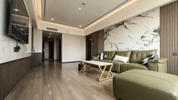 A modern living room with a green sofa, a coffee table, and a TV mounted on the wall. - Apollo Hotel (Yucheng)
