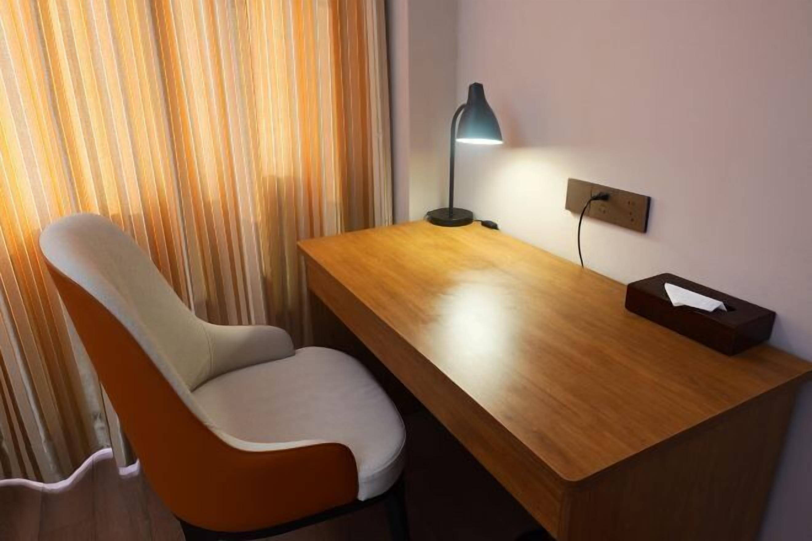 Ein Zimmer mit einem Holztisch, einem Stuhl, einer Lampe und einer Taschentuchbox.