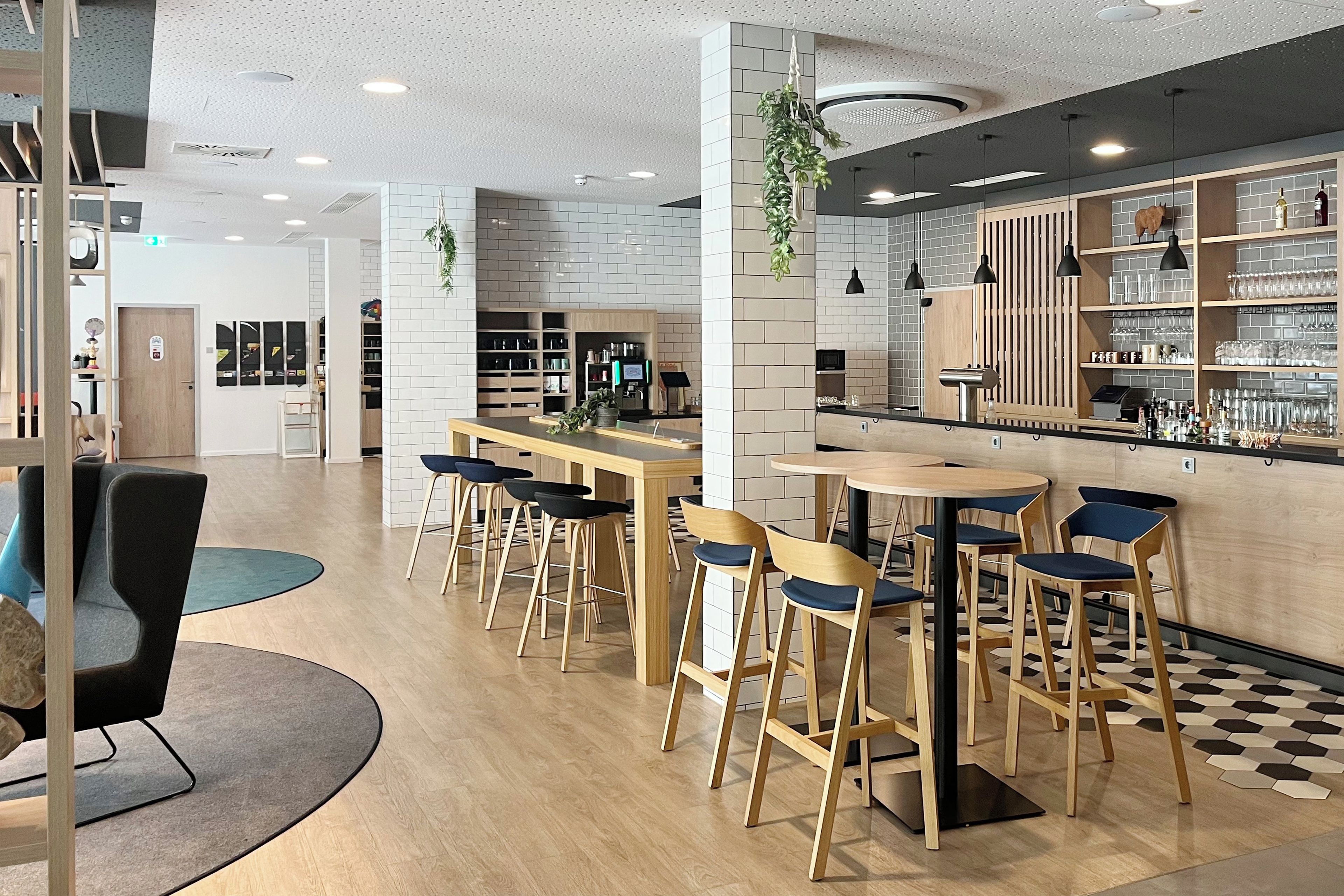 A modern cafe interior with wooden tables and chairs, a bar area with shelves of glasses, and a checkered floor pattern.