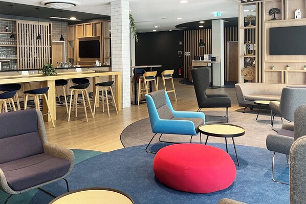 Un área de lounge moderna con arreglos de asientos, un bar y una recepción.