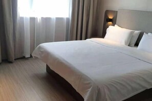 A neatly made bed with white linens in a hotel room. - HanTing Hotel (Lijiang Old Town Dashuiche) (Lijiang)