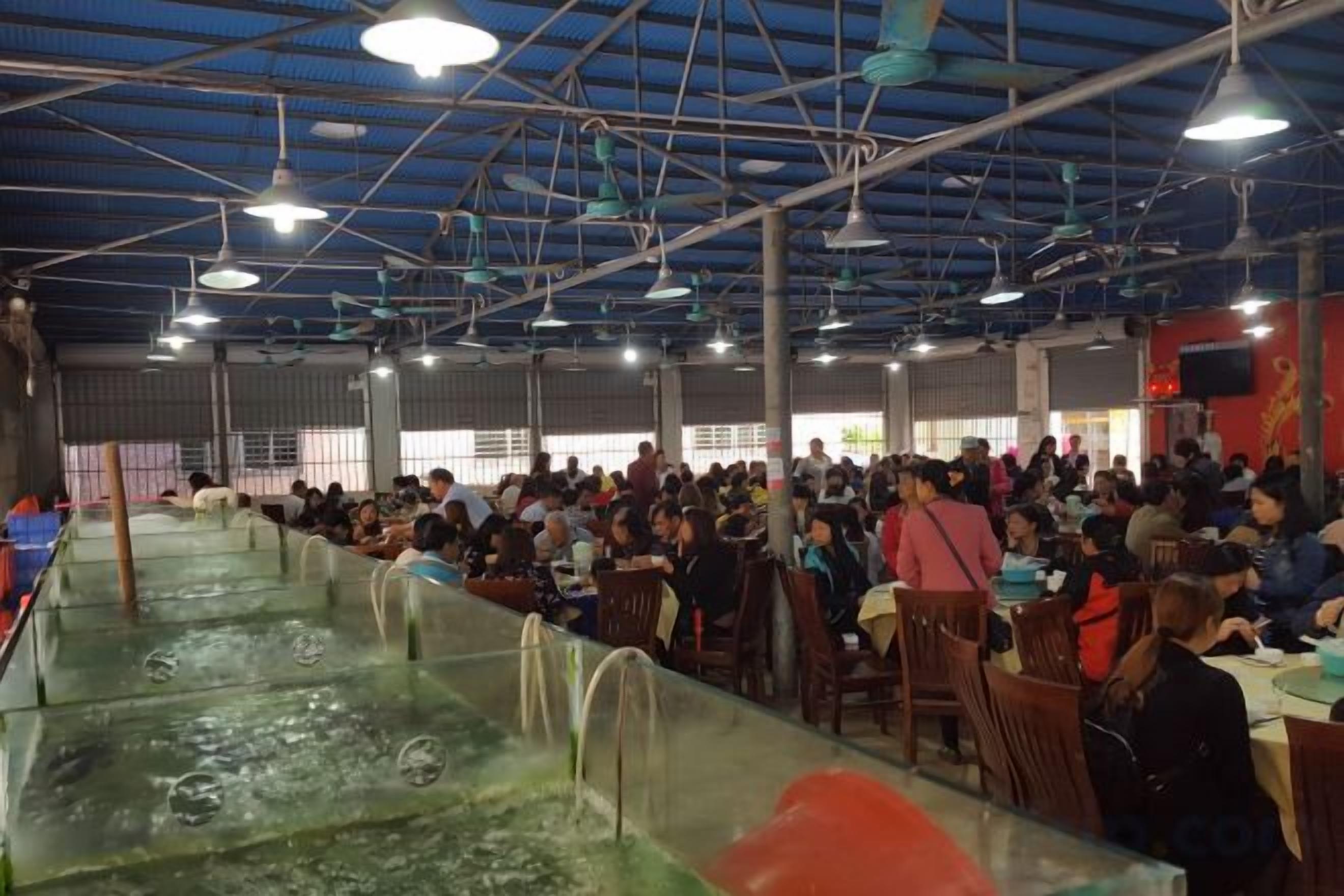 A large indoor space with a high ceiling, multiple tables and chairs, and a long counter with a water feature.