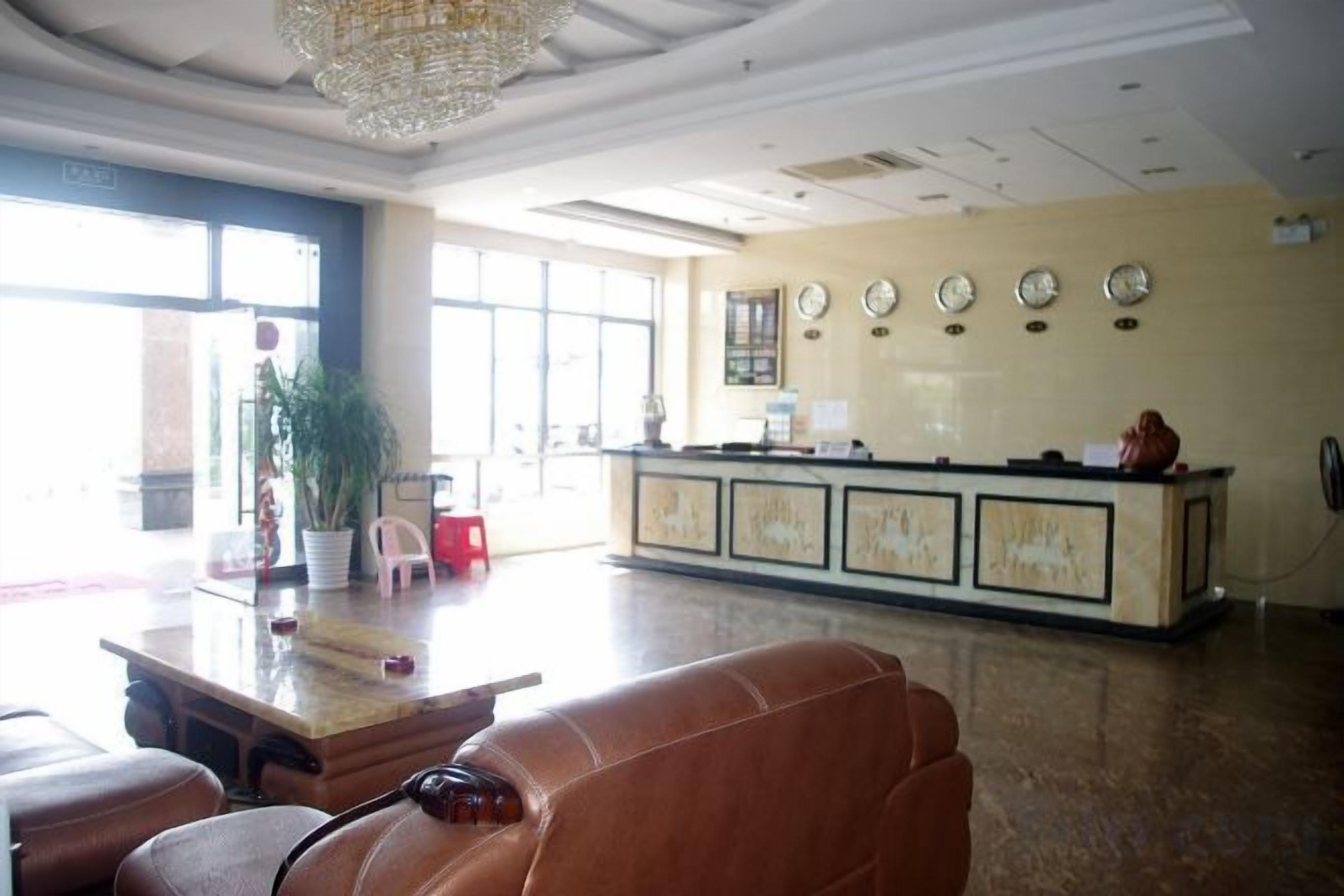 A hotel lobby with a reception desk, seating area, and large windows.