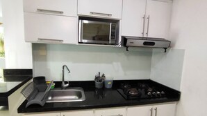 A kitchen with white cabinets, a stainless steel sink, a microwave, and a stove. - EM3-1 APARTAMENTO 1 HAB ZONA RESIDENCIAL (Cartagena)