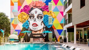 A pool area with a mural, lounge chairs, and a building with a geometric facade.