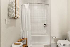 Un baño con bañera, inodoro y un perchero con toallas ordenadas.
