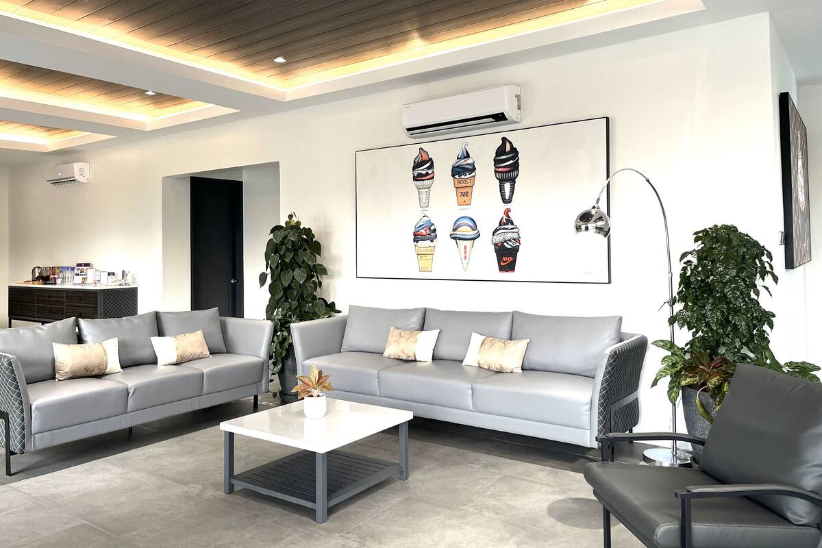 Una sala de estar moderna con un sofá gris, una mesa de centro y un aire acondicionado de pared.