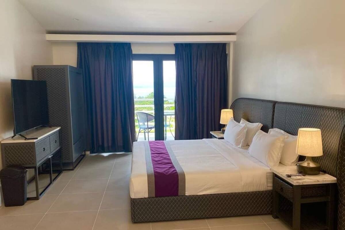 Un cuarto de hotel con una cama grande, televisión, escritorio y vista al exterior.