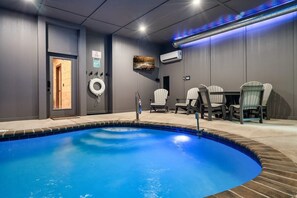 A swimming pool with a tiled edge, a door, and a seating area with chairs.