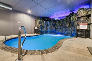 A pool with a waterfall feature and a warning sign. - Cabin· Pool·Hot Tub·Sauna·Creek·Sleeps 12 (Sevierville)
