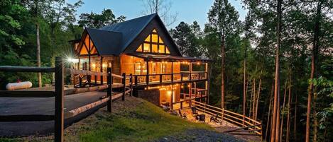A cabin with a balcony, surrounded by trees.