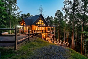 A cabin with a balcony, surrounded by trees.