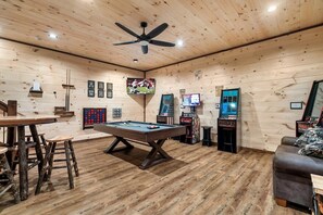 A pool table in a room with wooden walls and ceiling, a ceiling fan, and arcade games. - Cabin· Pool·Hot Tub·Sauna·Creek·Sleeps 12 (Sevierville)