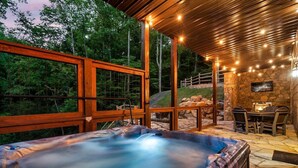A hot tub with a stone wall and outdoor seating area. - Cabin·Indoor Pool·Sauna·Game Rm·Creek·15 Min to NP (Sevierville)
