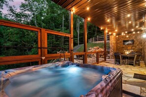 A hot tub with a stone wall and outdoor seating area.