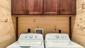 A laundry area with two white front-loading washers and a wooden cabinet above. - Cabin·Indoor Pool·Sauna·Game Rm·Creek·15 Min to NP (Sevierville)