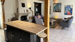 Amplia sala de estar con techo de madera, chimenea, zona de bar y muebles modernos.