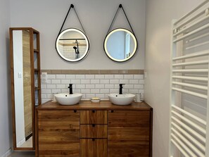 Ein Badezimmer mit zwei Waschbecken, Holzschränken und zwei Spiegeln an der Wand.