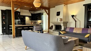 Una sala de estar moderna con un sofá gris, una chimenea y una cocina al fondo.