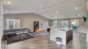 Un salon moderne comprenant un canapé, une table basse et un petit coin cuisine avec un évier et un plan de travail.