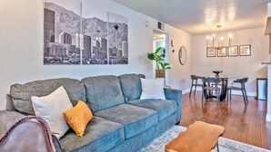Un salon avec un canapé gris, une table basse et un coin repas comprenant une table et des chaises.