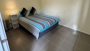 A bedroom with a bed, a nightstand, a lamp, and a radiator. - Brandnew bedroom in a beautiful suburb  (Saint Albans)